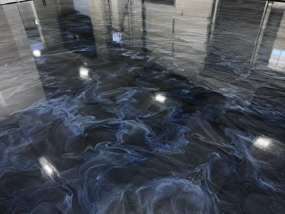 Close-up of a metallic epoxy floor with a charcoal and navy marbled swirl pattern